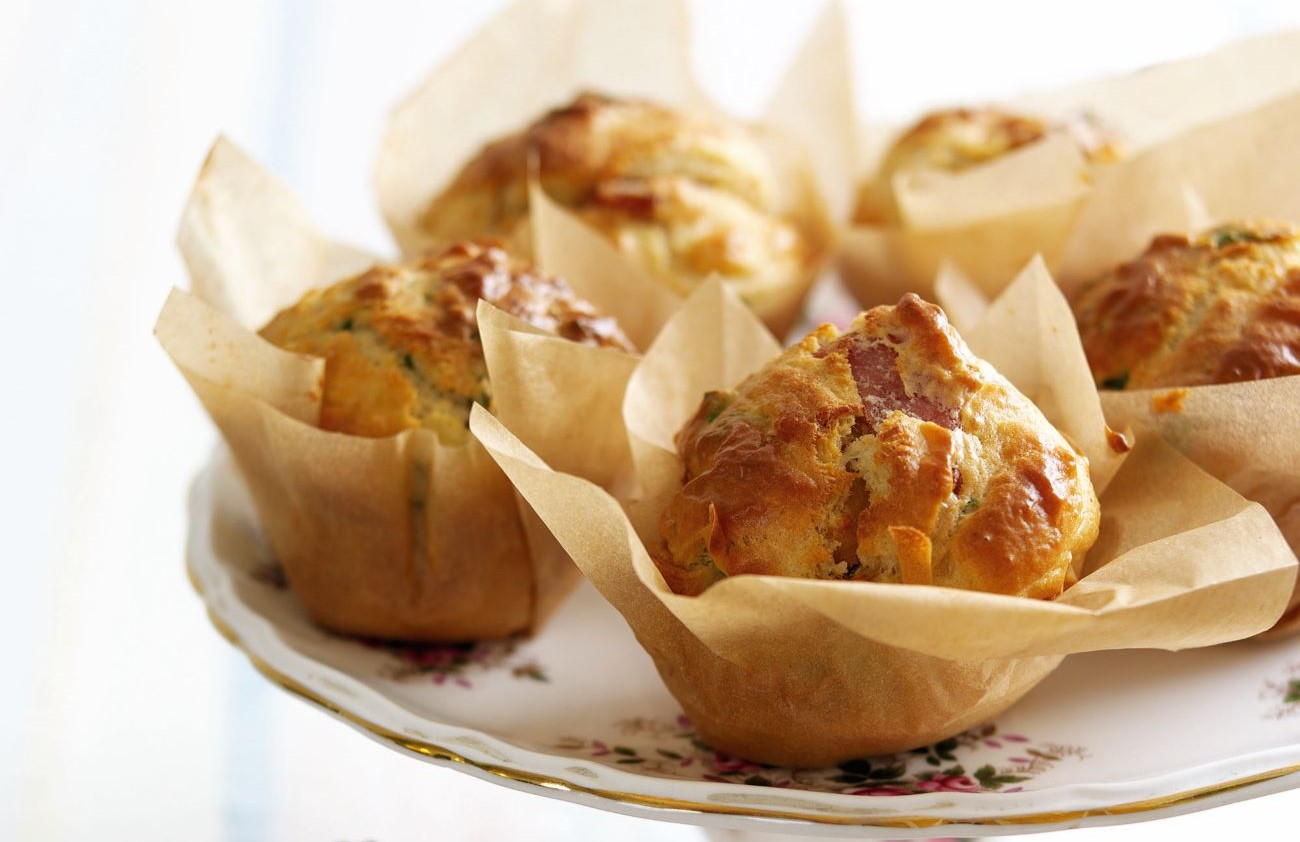 Bacon onion and basil muffins in brown liners, on a cake stand