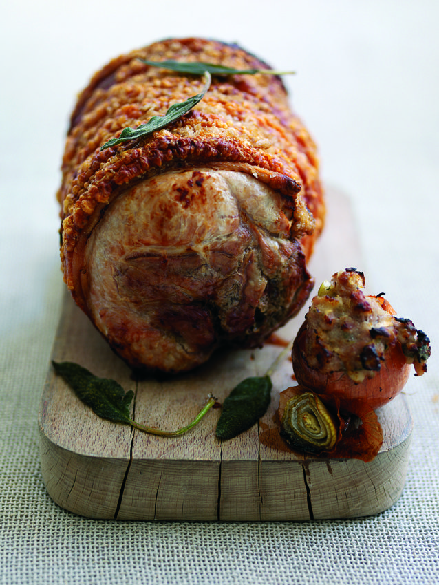 Roast leg of pork served on a wooden chopping board, with stuffing ball