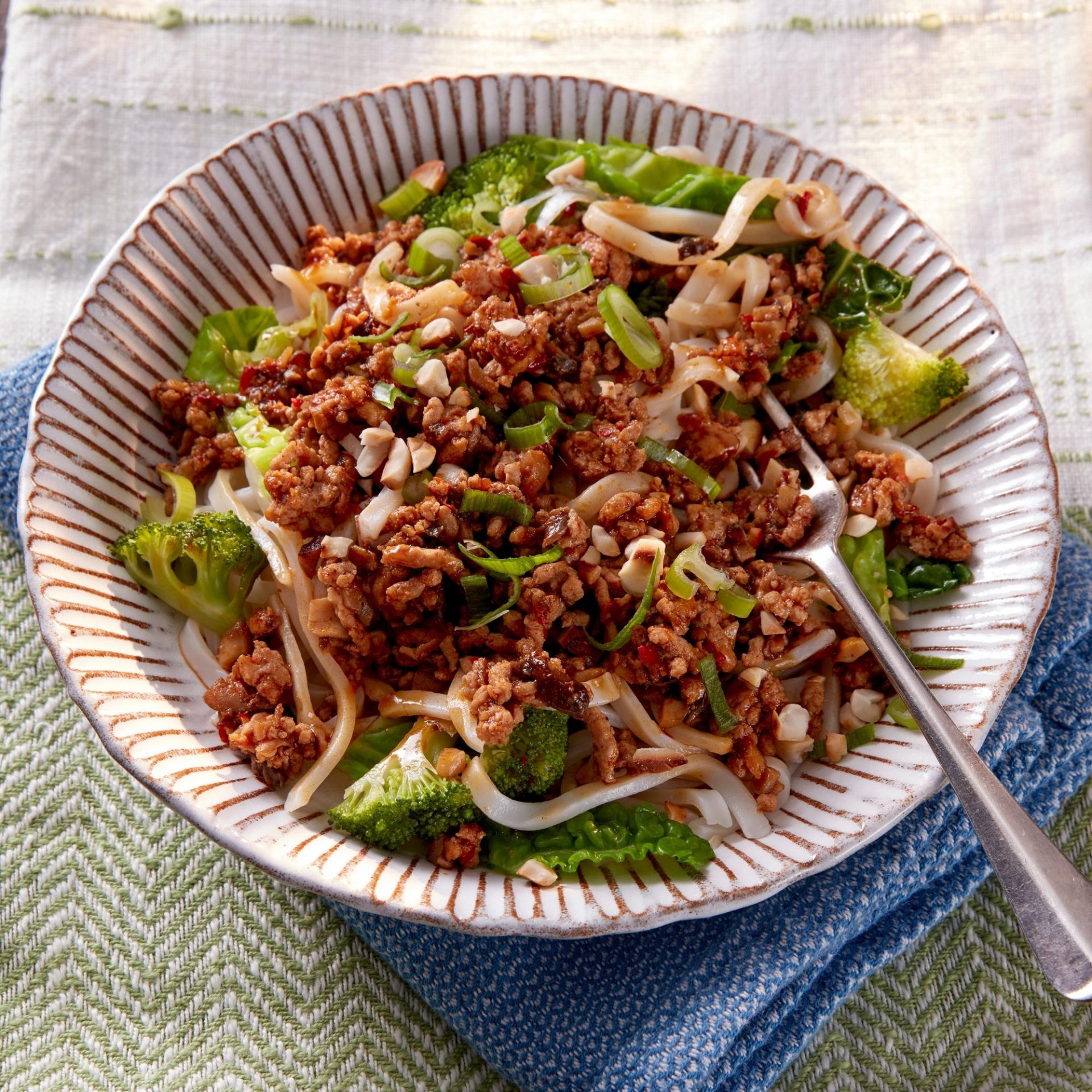 Bowl filled with pork mince and noodles, with a fork