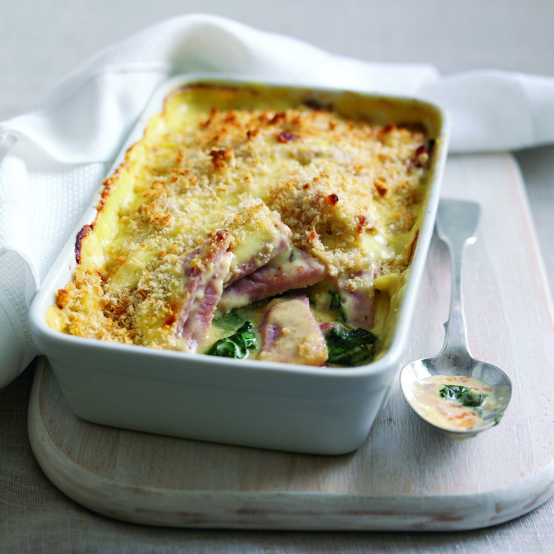 Gammon florentine served in a big white casserole dish, spoon on the side
