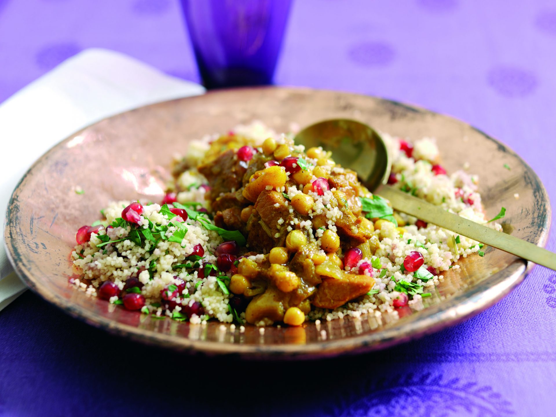 Gammon tagine on a bed of pomegranate and parsley couscous, on a dish with spoon