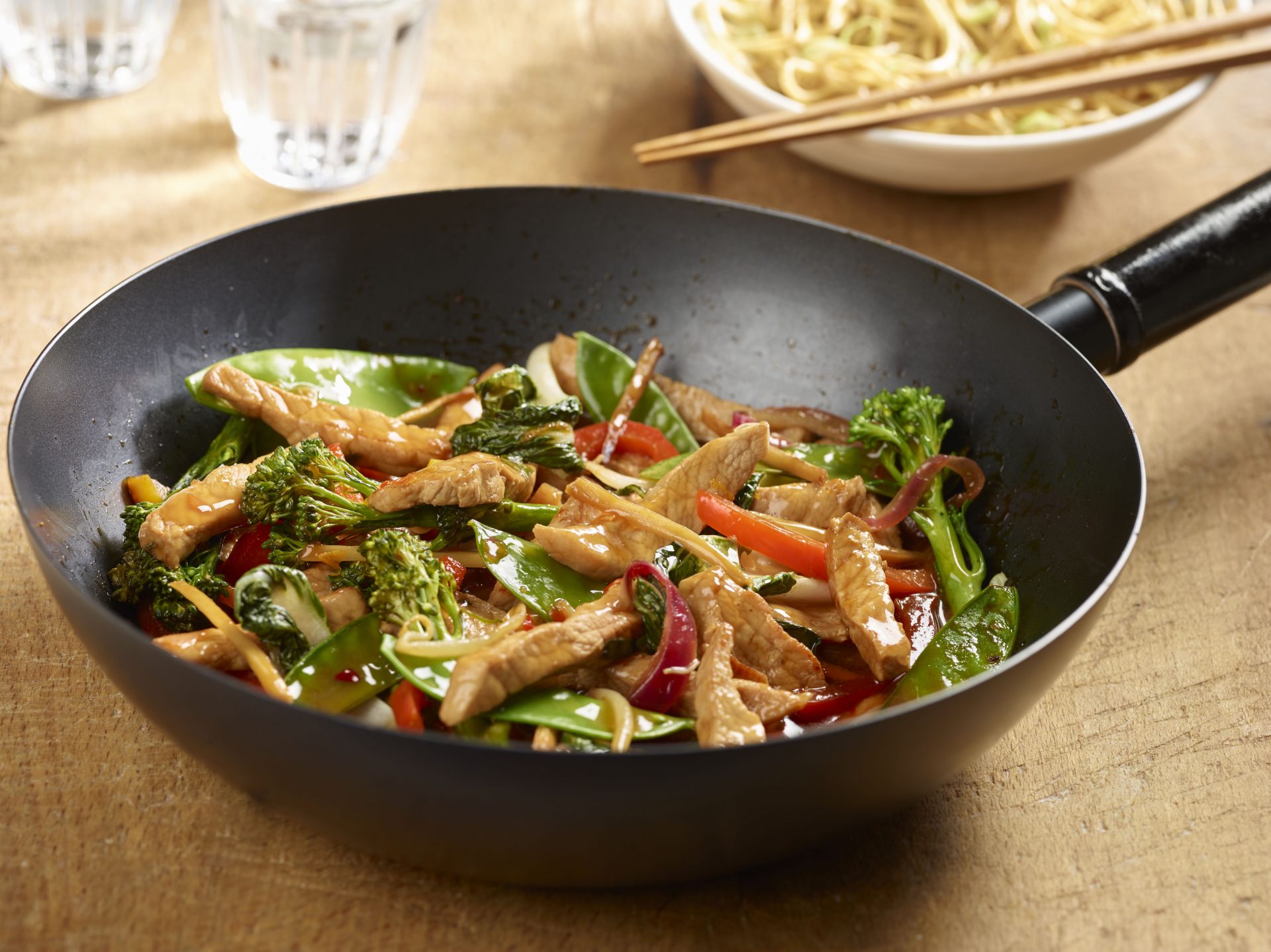 Large black frying pan containing a ginger and orange pork stir fry