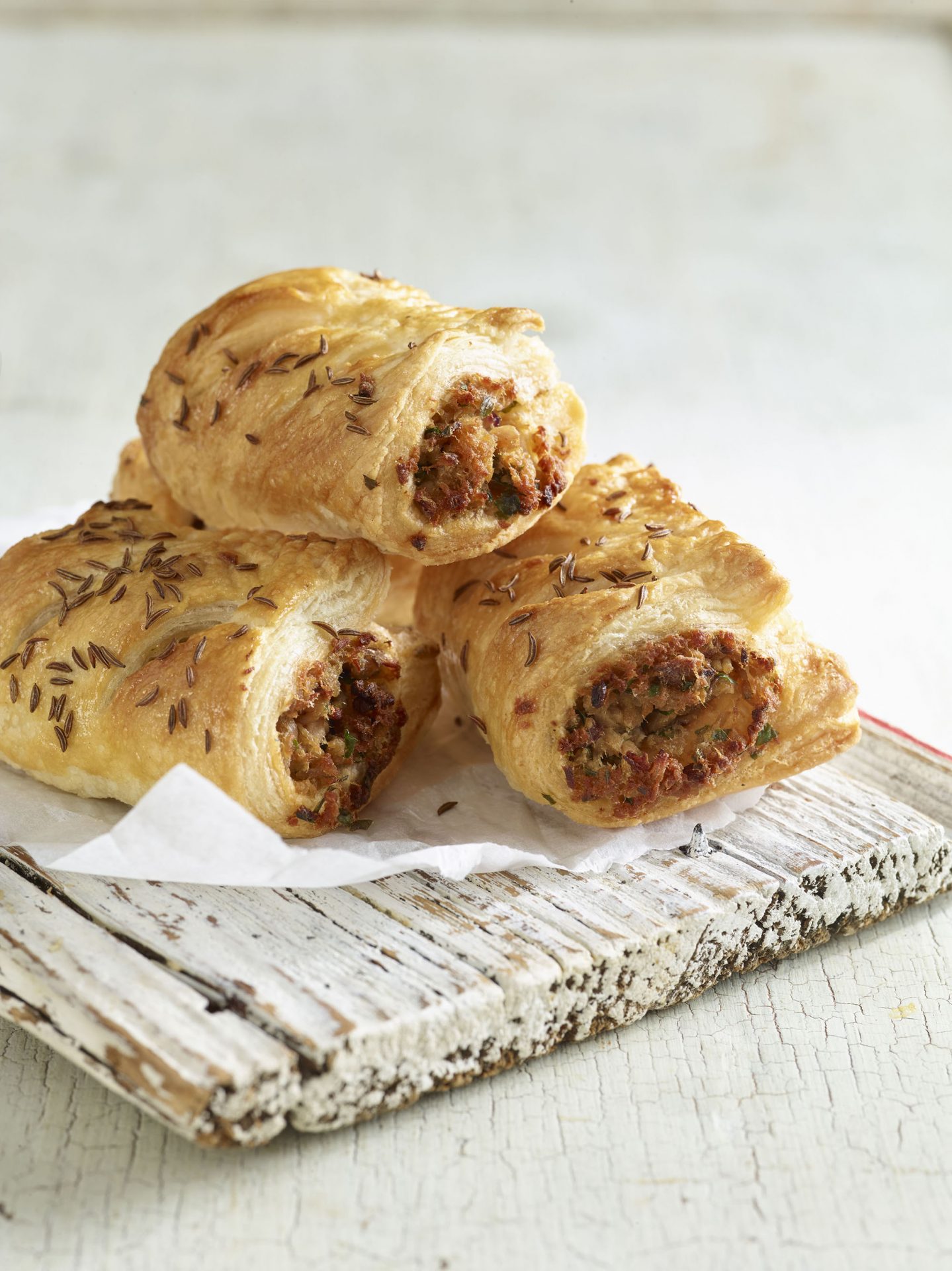 Pulled pork sausage rolls on a white washed board