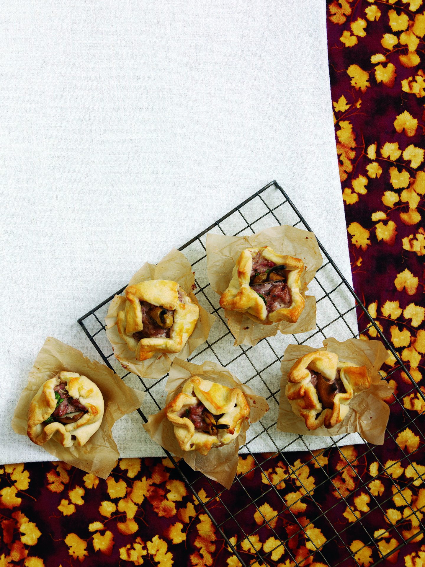 Five mini pork and pear pies on a wire baking rack