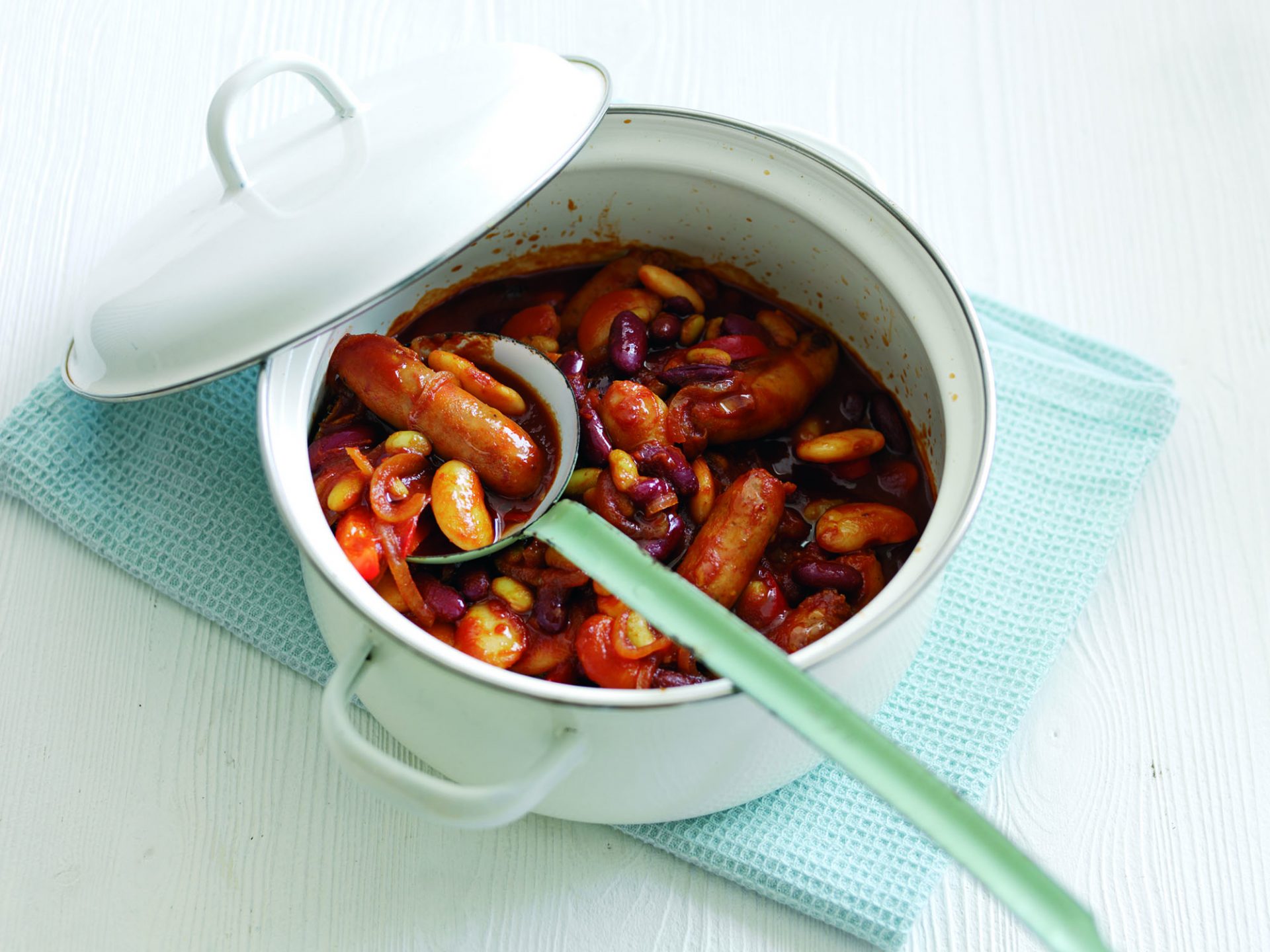 Sausage and bean casserole in a pot with a spoon