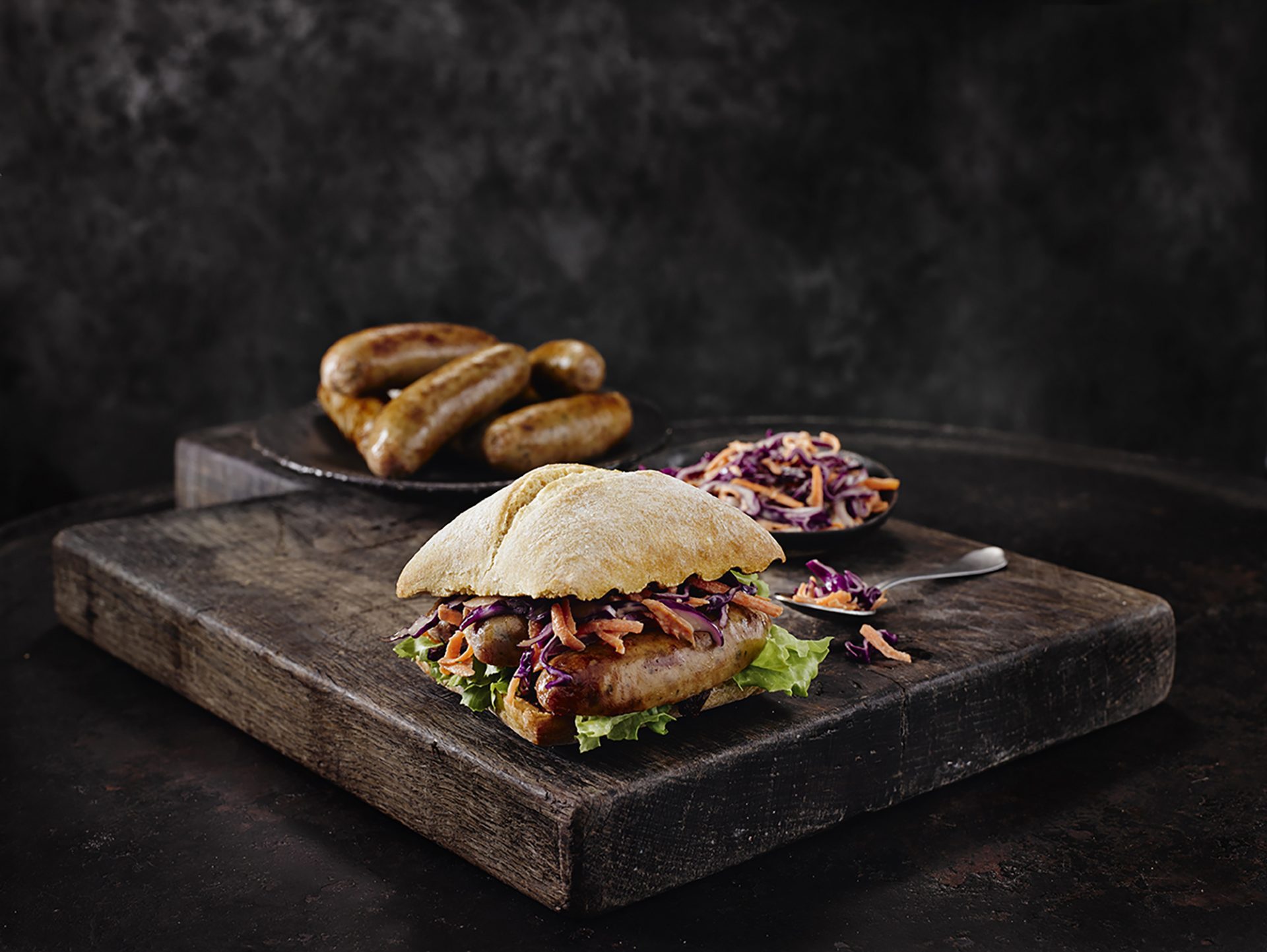 Sausage burgers with homemade slaw served on a dark board with dark backdrop