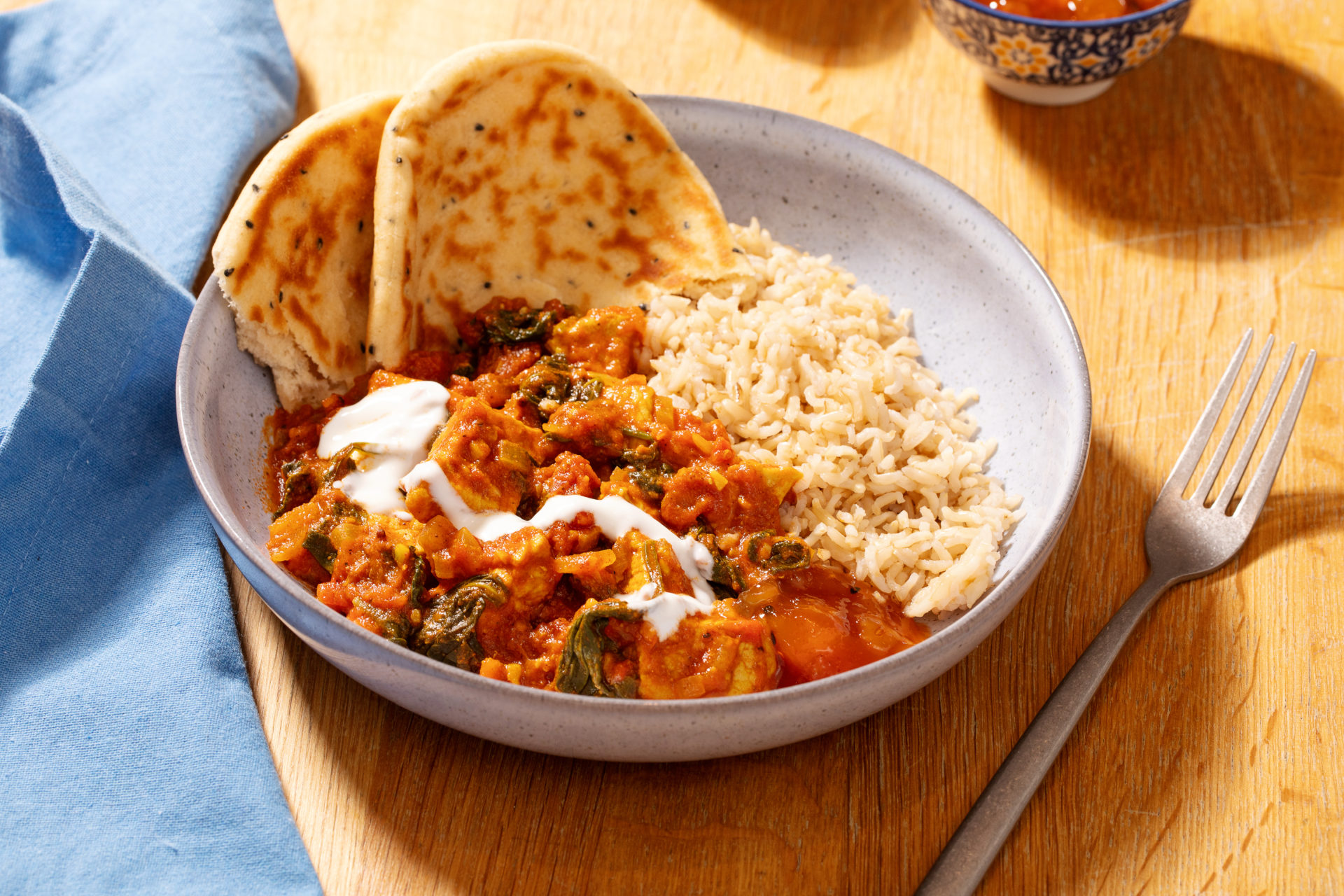 Bowl of Easy pork curry with naan and drizzle of yoghurt